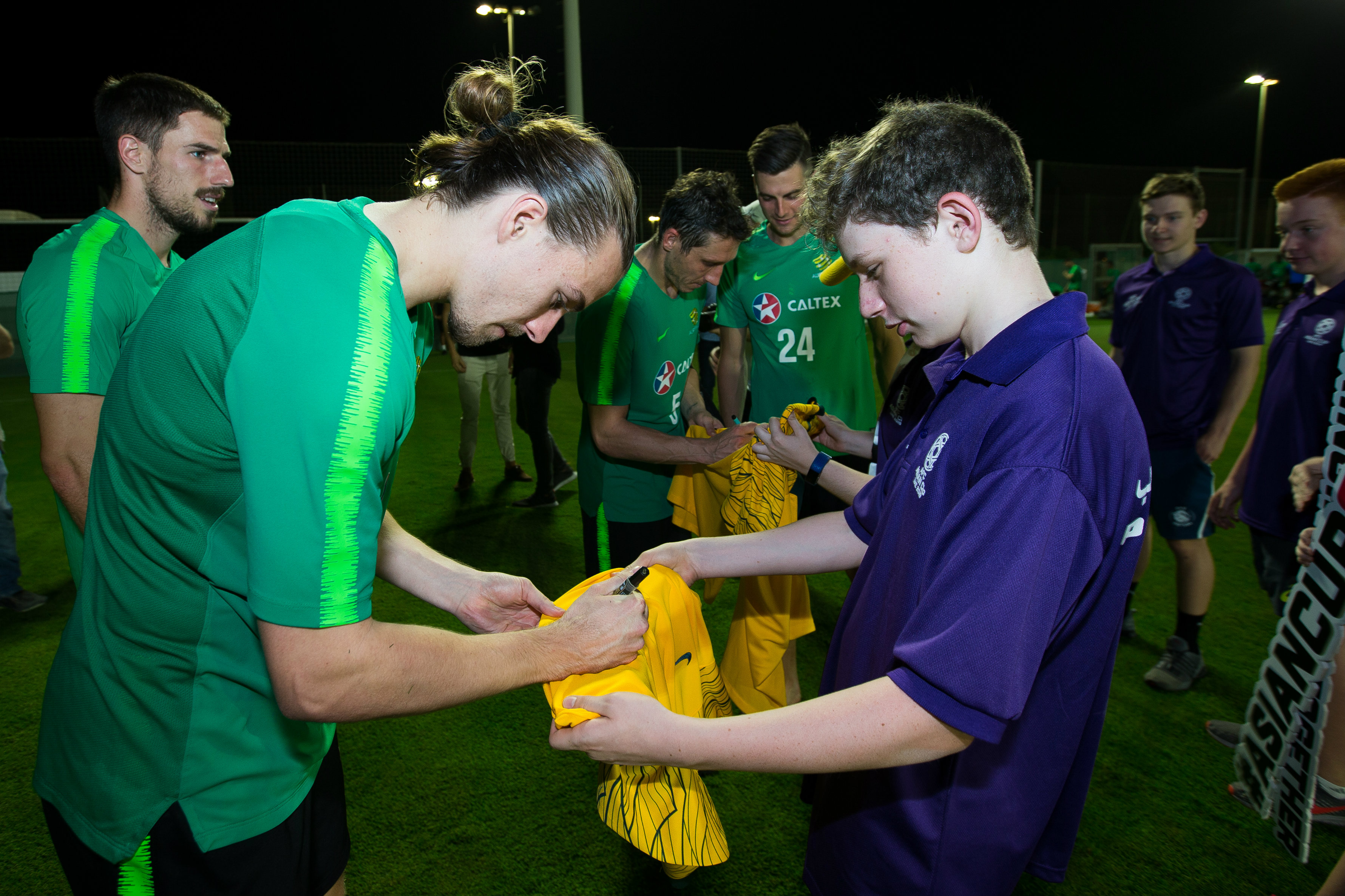 Jackson Irvine signs a jersey for a young fan.