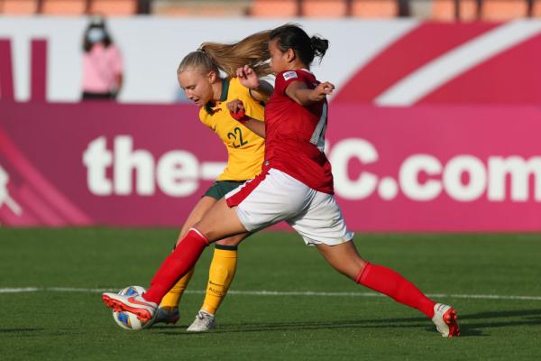 Holly McNamara strikes the ball as an Indonesia defender attempts to block it